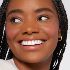 Rare Beauty applying blush with fingers demonstrating easy, streak-free blending