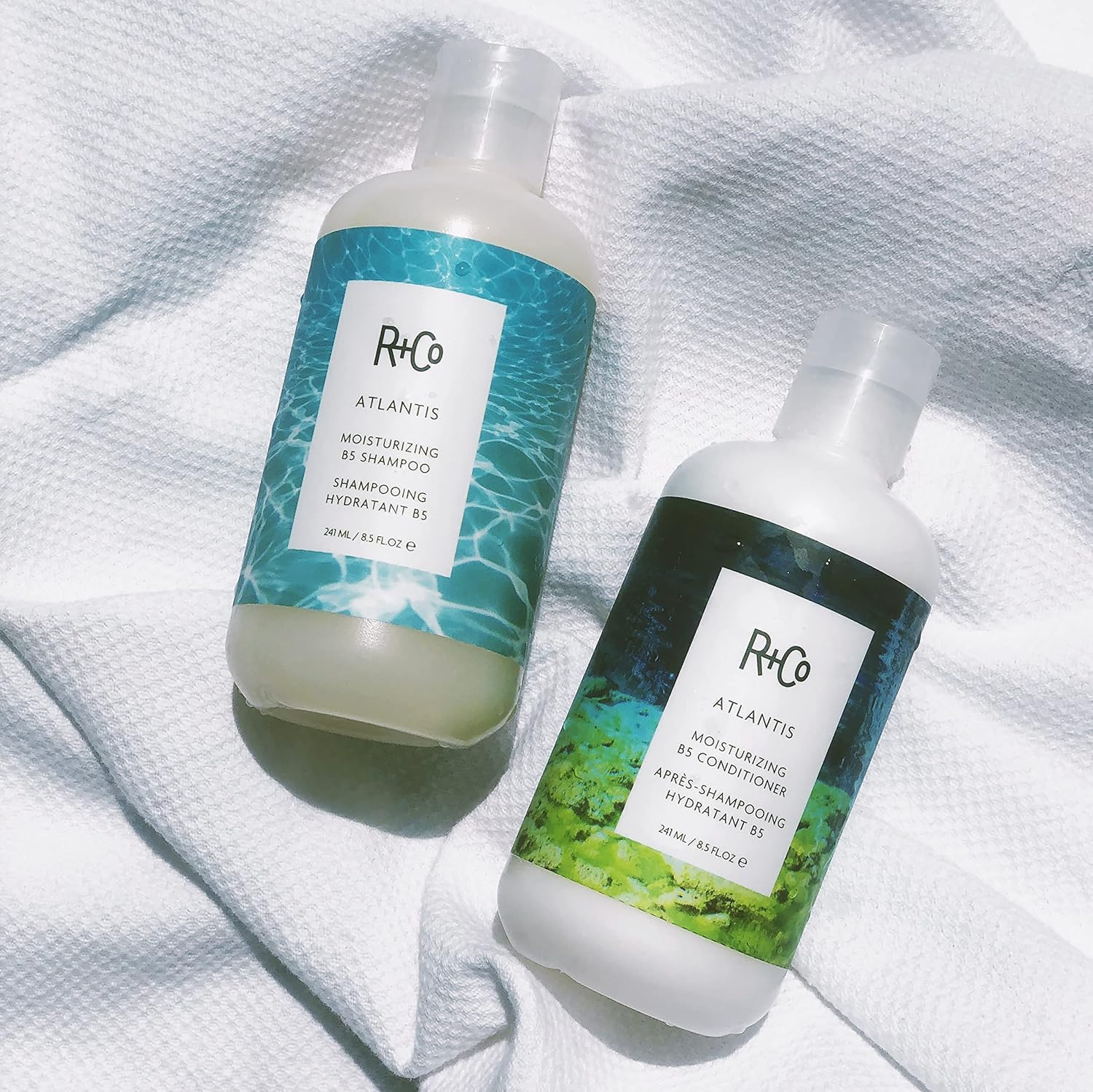 R+Co ATLANTIS next to a ruler showing 8.5 fl oz scale and travel-friendly benefit