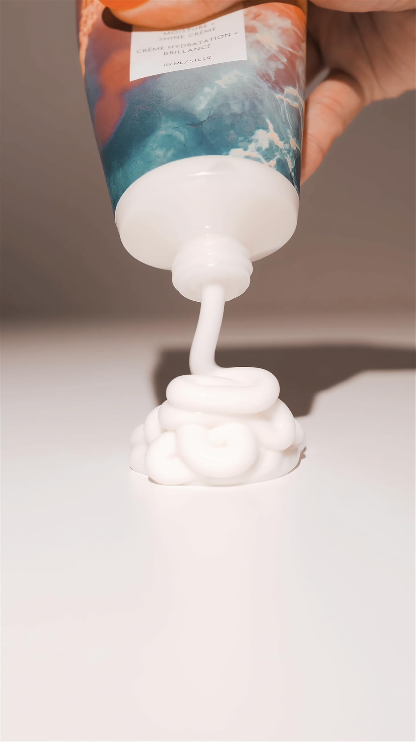 R+Co HIGH DIVE size comparison beside a hand illustrating the 1.7 oz travel-friendly benefit