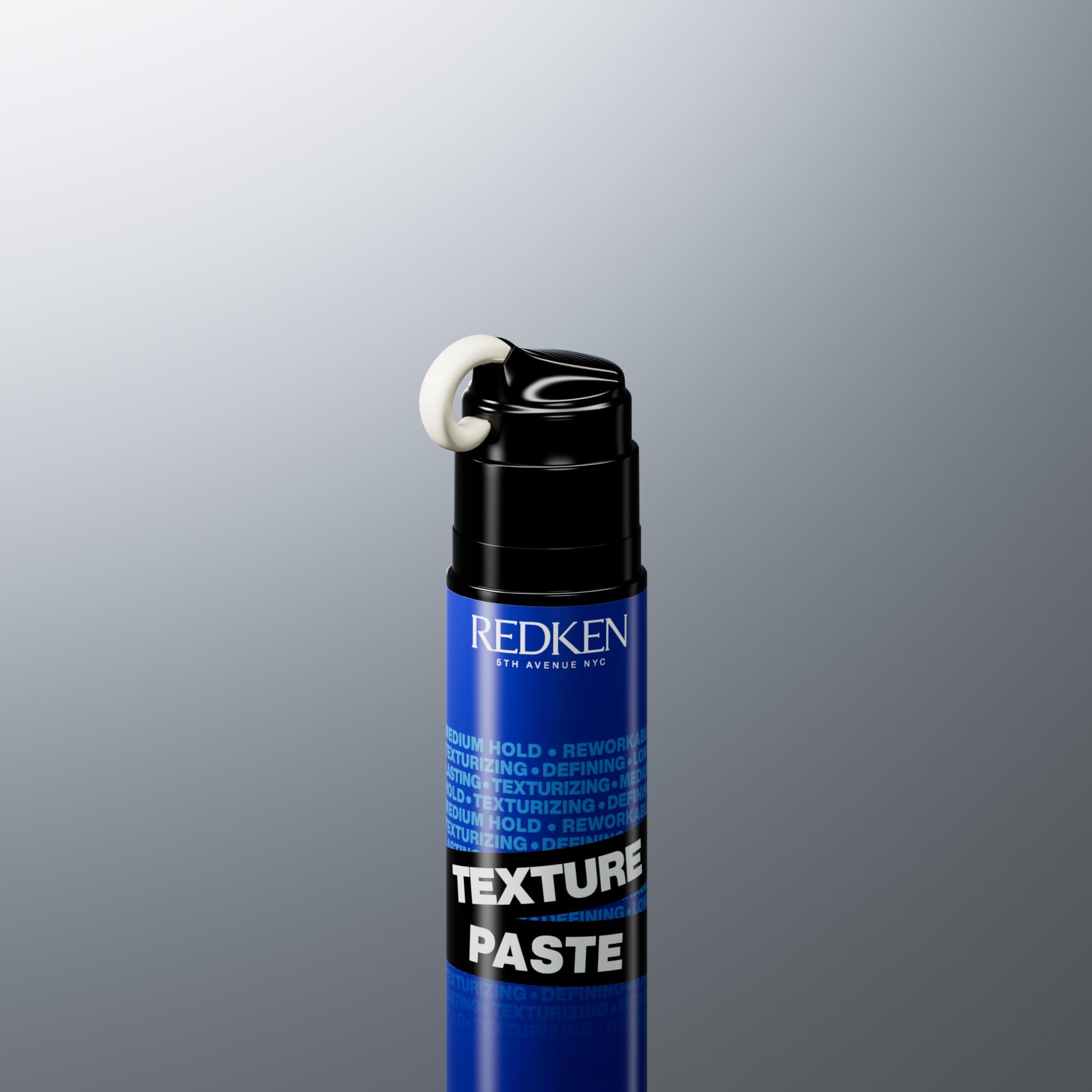 Redken paste next to ruler showing 3.4 oz size for travel-friendly convenience
