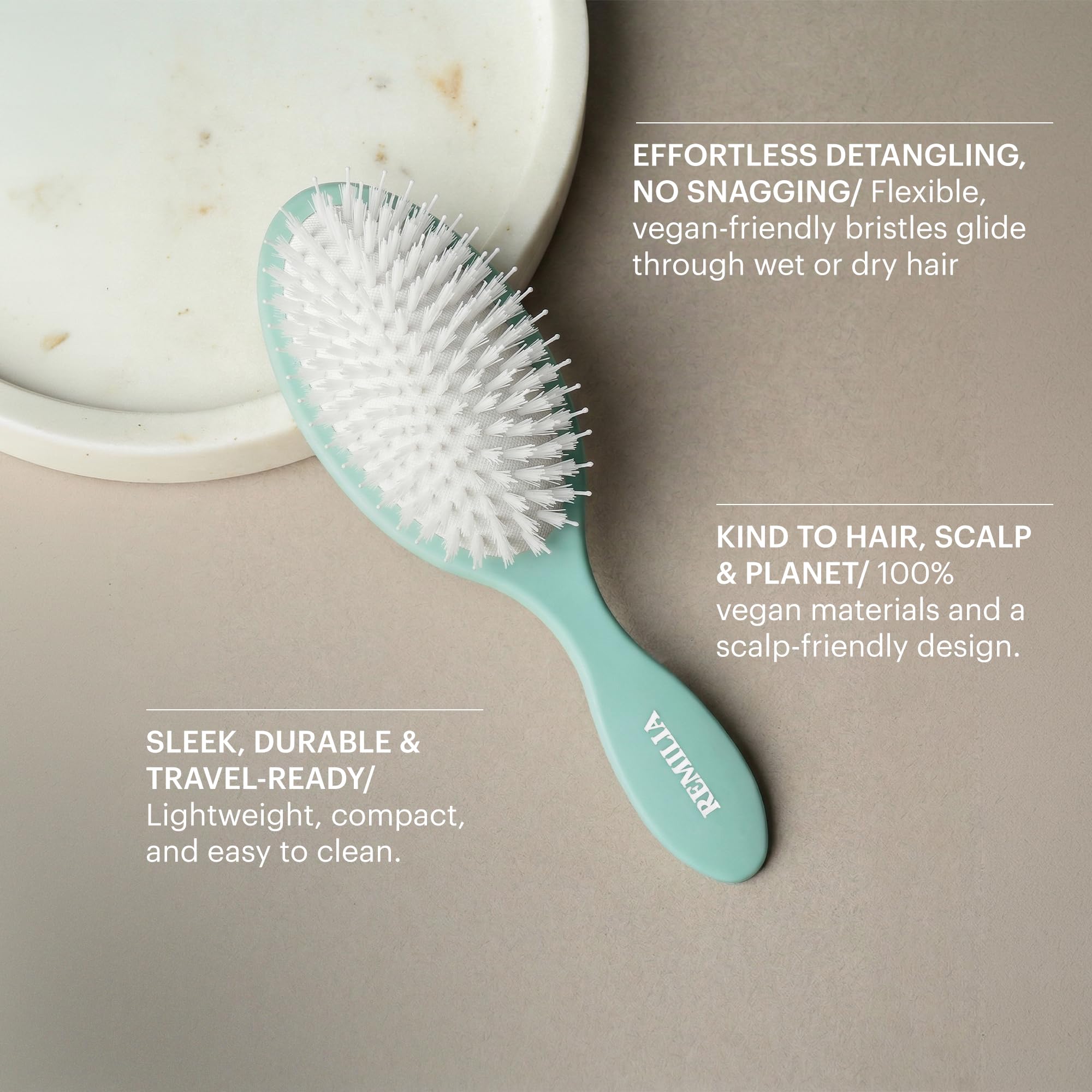 Remilia Hair brush held in hand illustrating compact size and travel convenience