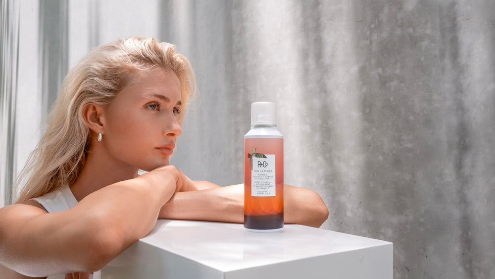 R+Co bottle beside hand to show 5 oz scale and travel-friendly benefit