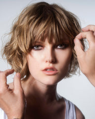 R+Co spraying on hair in salon to show styling protection and shine