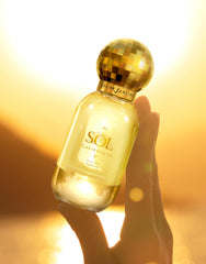 Hand holding Sol de Janeiro 50mL bottle indicating portable travel size