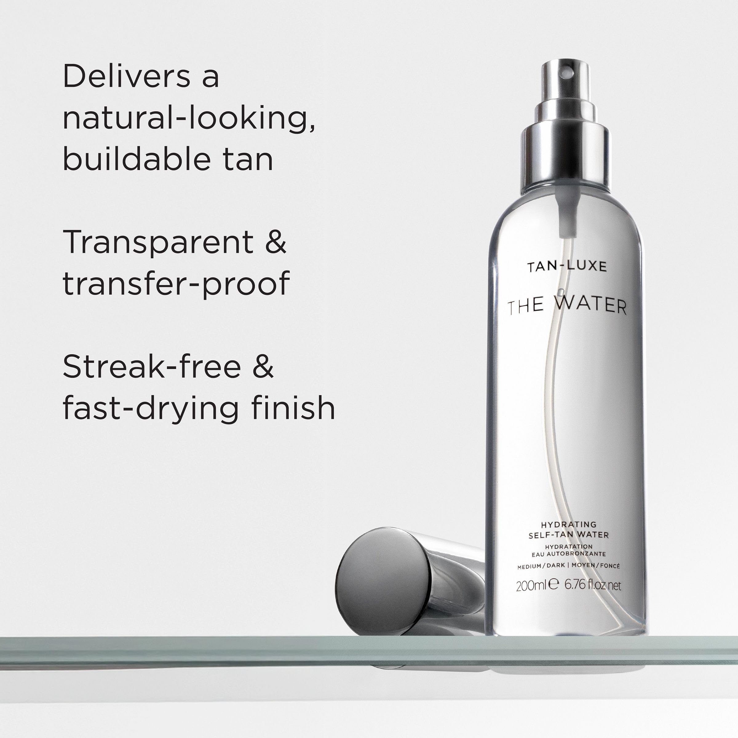 TAN-LUXE bottle in hand to show scale and easy at-home spray tanning convenience