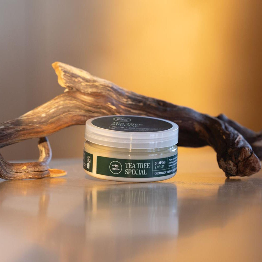 Tea Tree tube next to hand illustrating portable travel-friendly size benefit