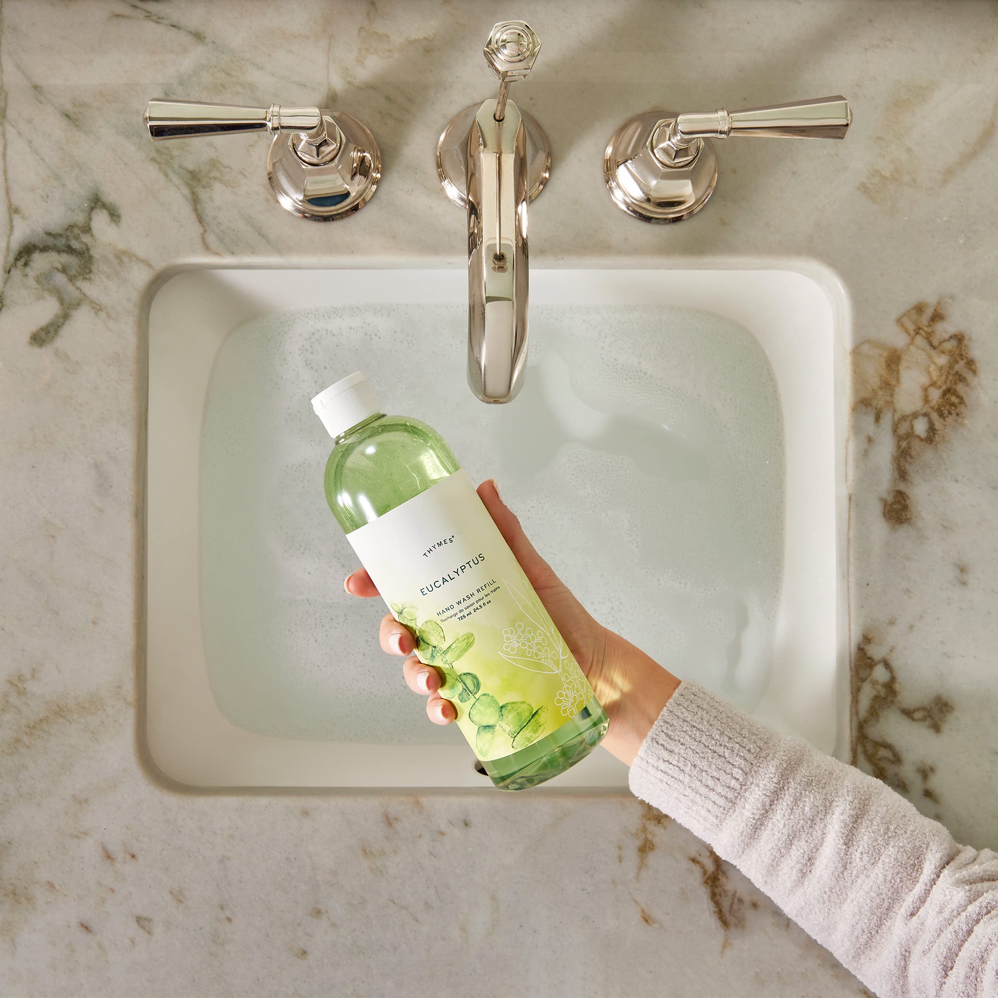 Thymes pouring liquid soap into a dispenser for easy refill convenience