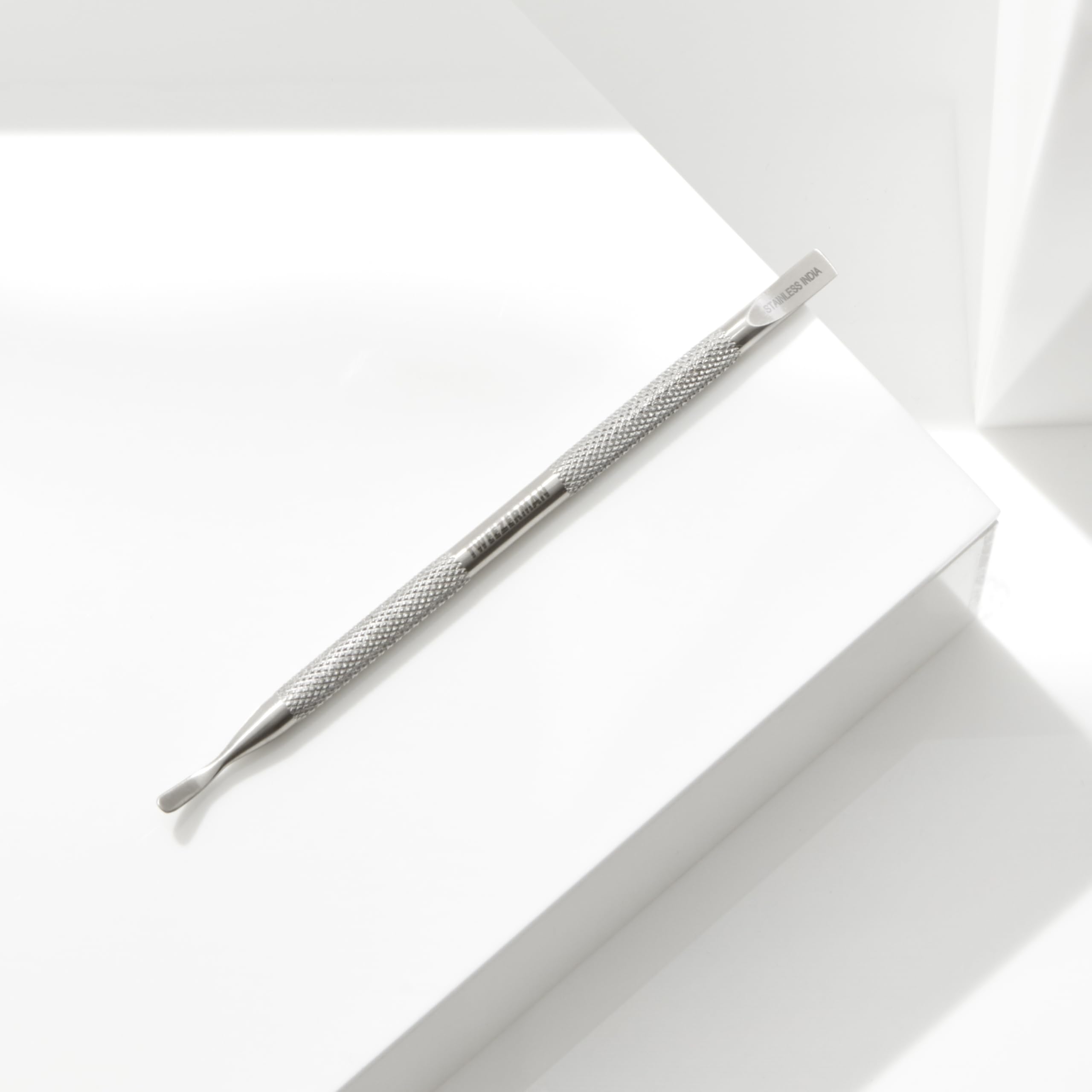 Tweezerman Pushy held beside fingers to show tool scale and accurate maneuvering
