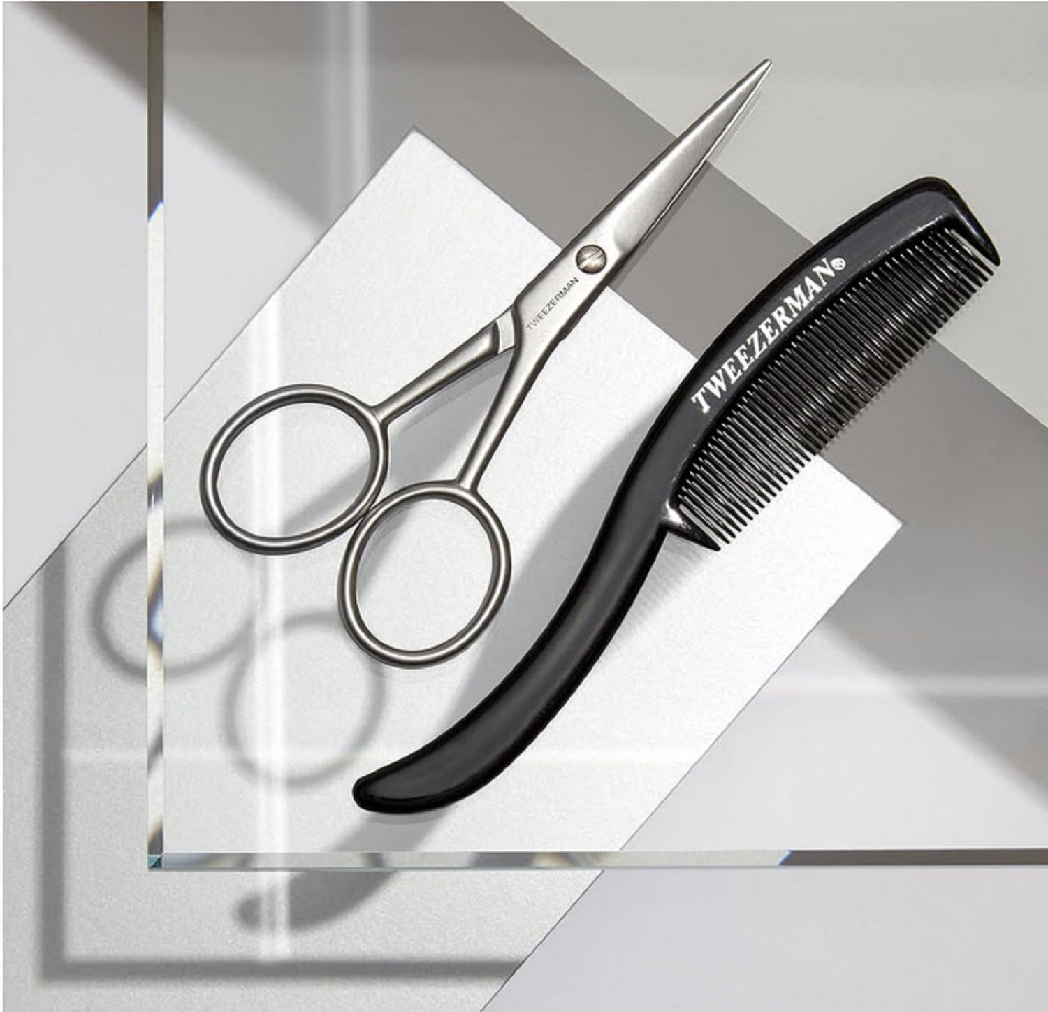 Tweezerman scissors held in hand demonstrating scale and ergonomic control for accurate snips