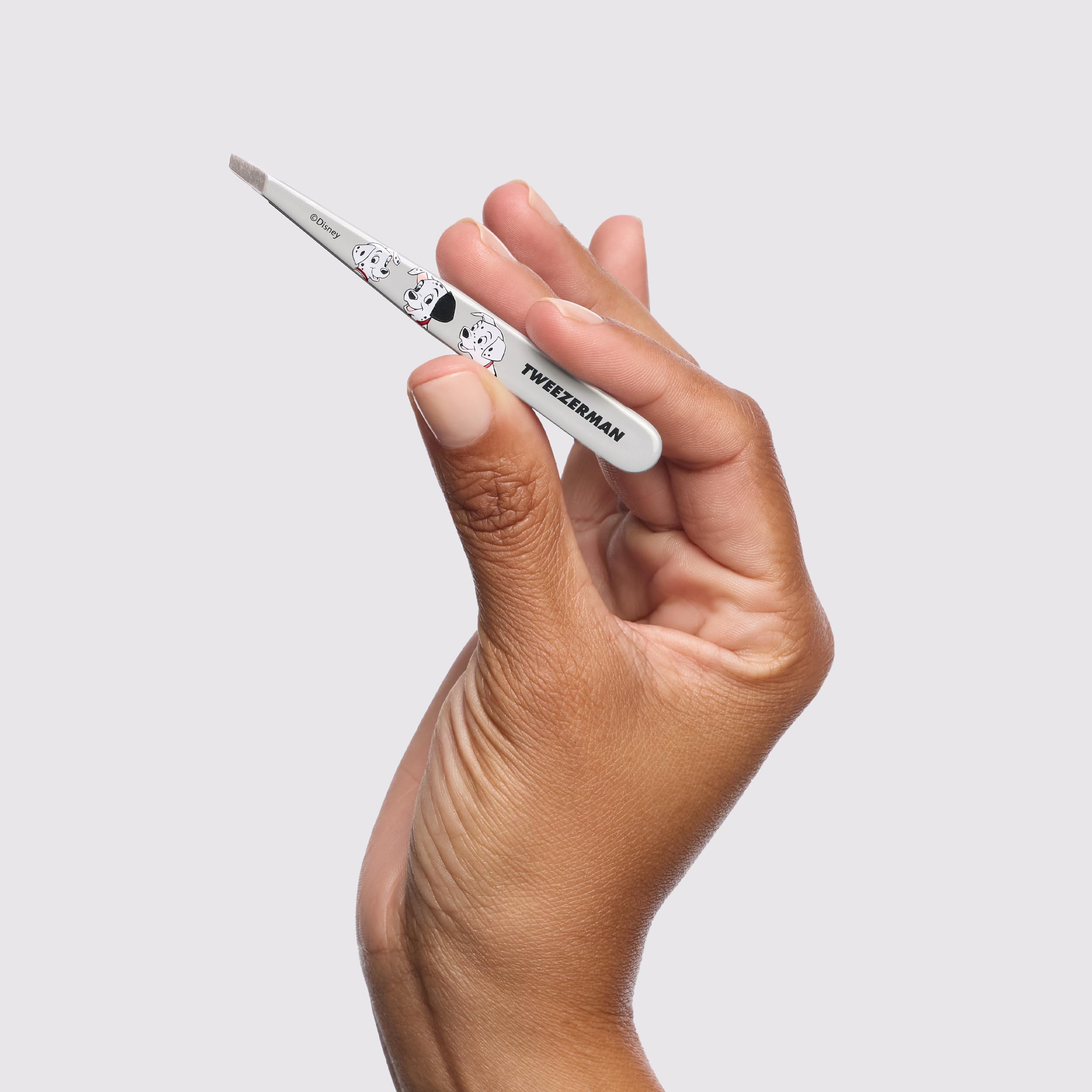 Tweezerman tweezer beside a ruler showing compact travel-friendly size