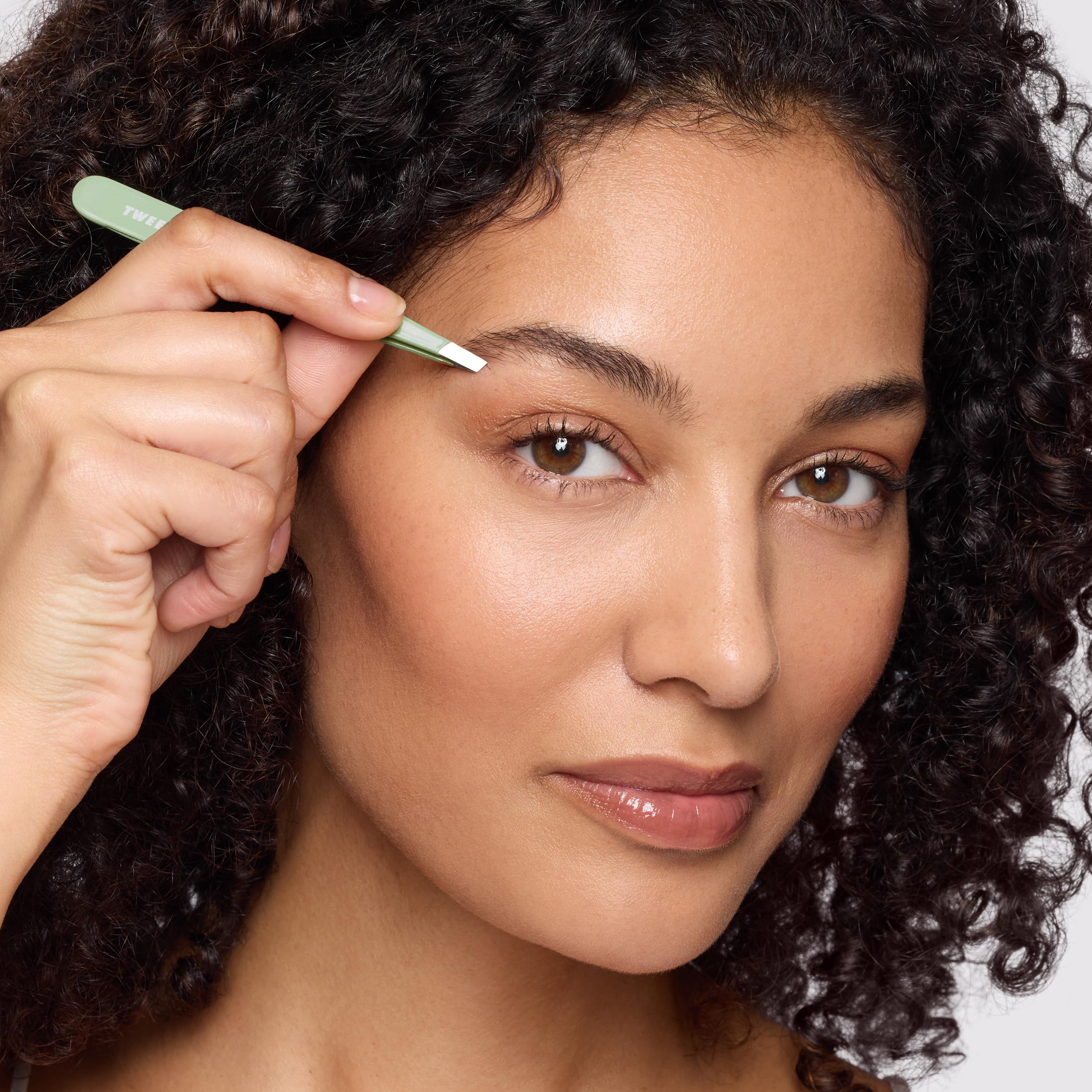 Tweezerman pistachio tweezer beside compact mirror for on-the-go grooming ease