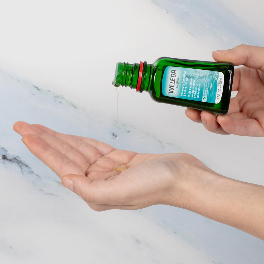 Weleda rosemary hair oil on a bathroom shelf in a lifestyle setting signaling daily routine use