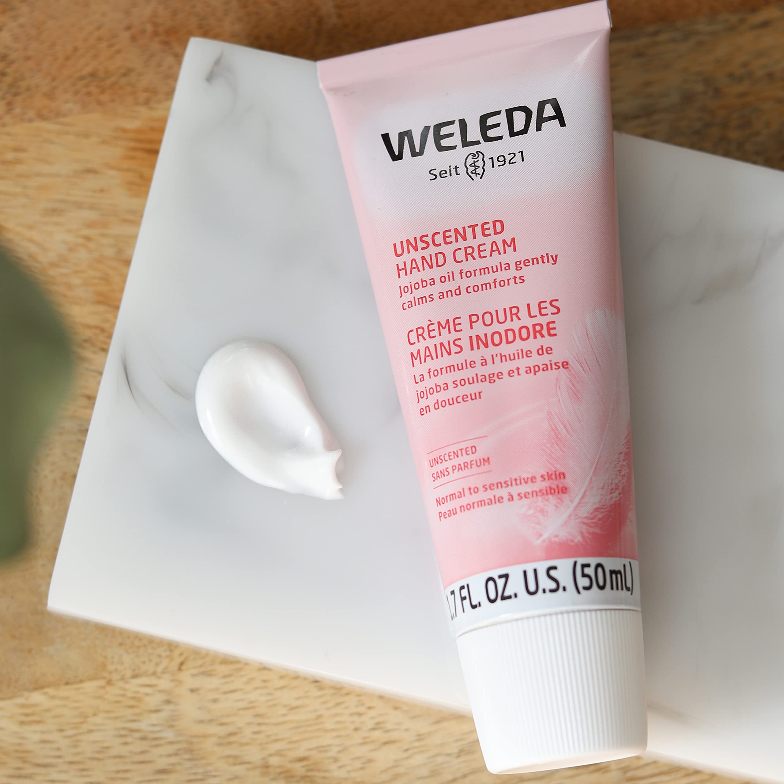 Weleda tube surrounded by botanical ingredients to emphasize natural sourcing and gentle care benefits